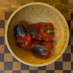 Ciotola di peperoni coperta con un piatto per creare vapore e facilitare la spellatura.