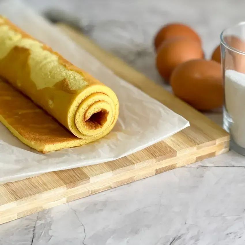 Pasta biscotto stesa su carta forno, elastica e pronta per essere arrotolata senza rompersi.