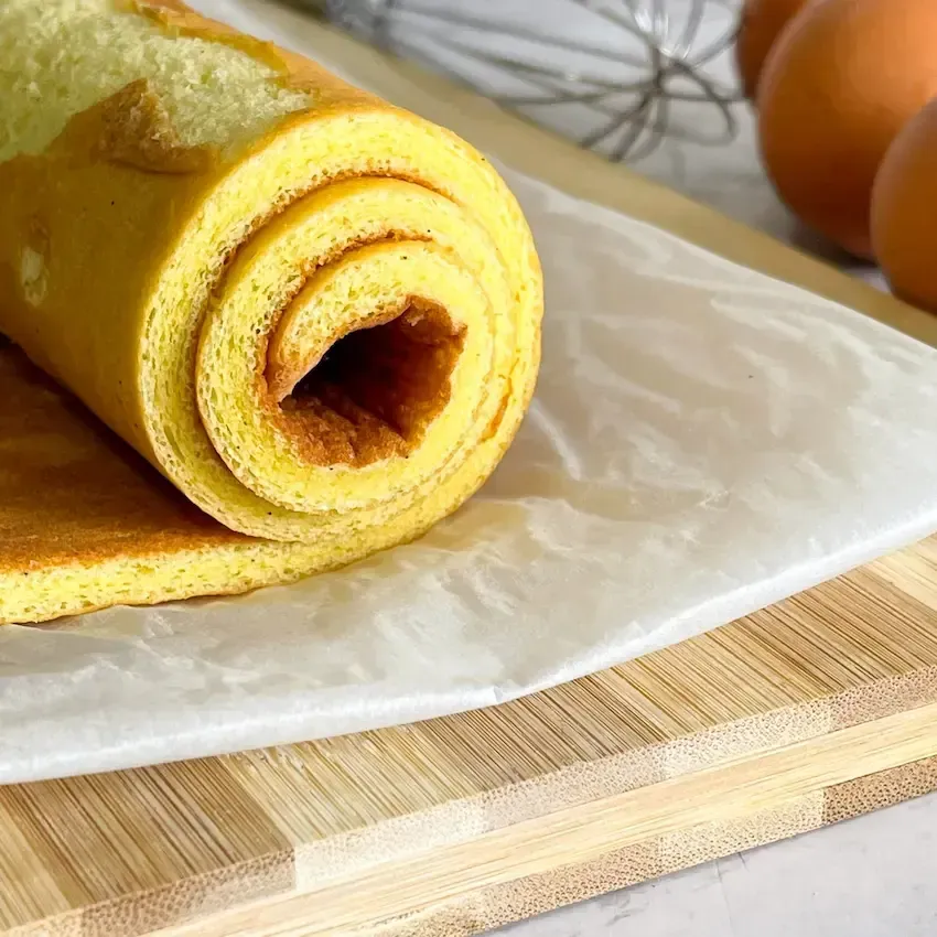 Pasta biscotto stesa su carta forno, elastica e pronta per essere arrotolata senza rompersi.