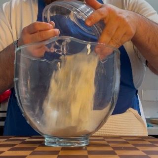 Un uomo sta versando qualcosa in una ciotola di vetro