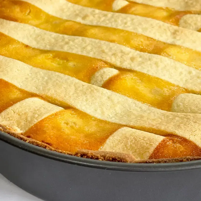 Pastiera napoletana appena sfornata con le classiche 7 strisce di frolla e zucchero a velo.