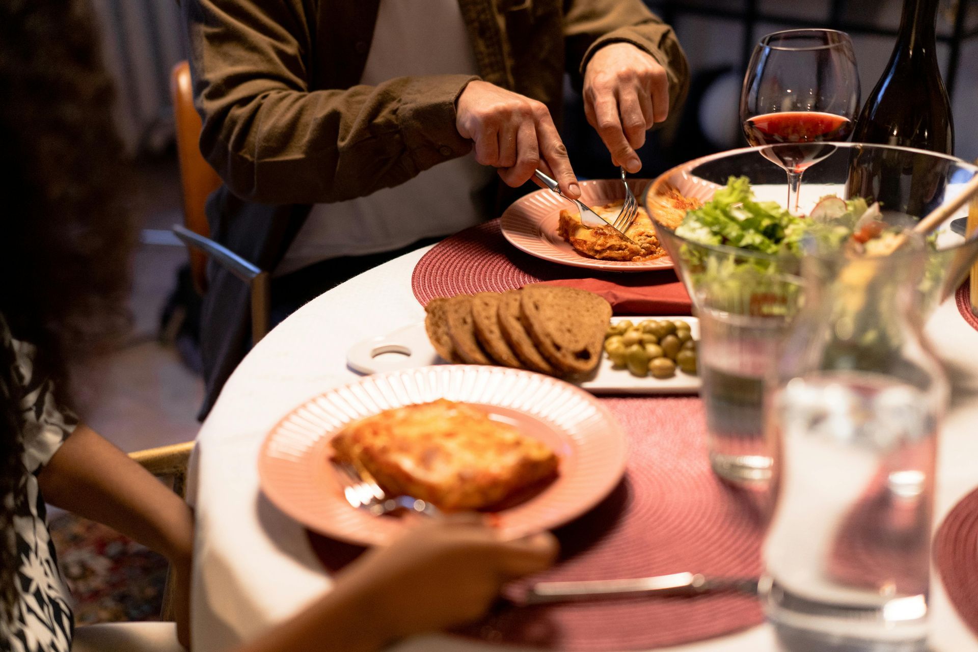 una tavola con piatti di lasagne alla bolognese e vino rosso abbinato 