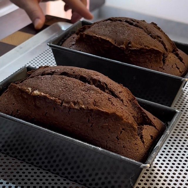 Plumcake al cioccolato appena sfornato, scuro e gonfio, che si intiepidisce.