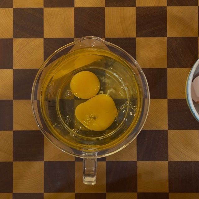 Ingredienti per il plumcake allo yogurt disposti in ordine in un contenitore alto.