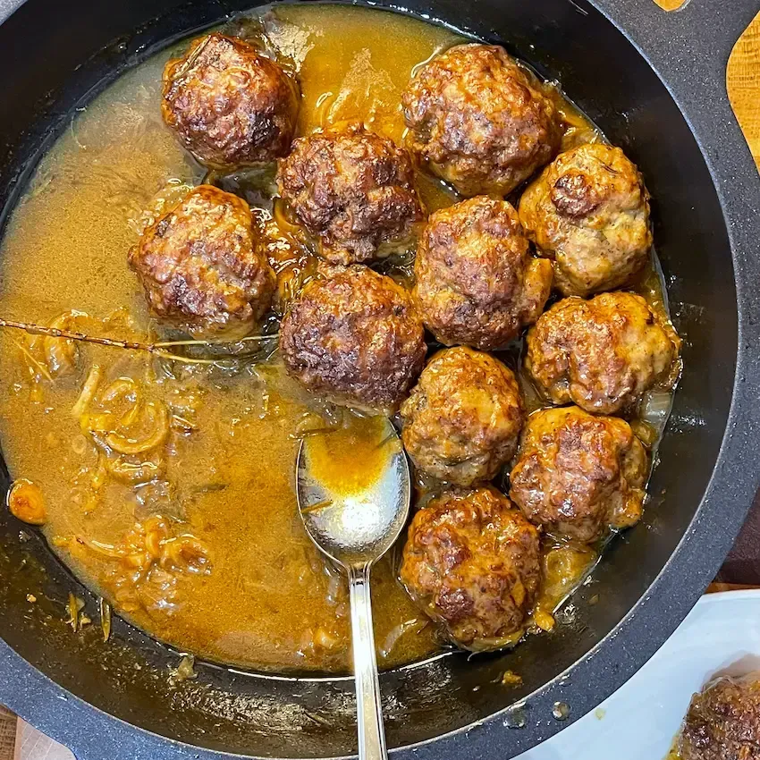 Padella fumante con polpette di carne morbide in padella che cuociono in un sughetto denso e profuma