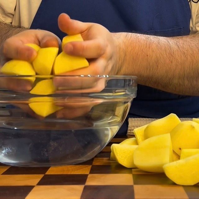 Spicchi di patate immersi in una ciotola di acqua fredda.
