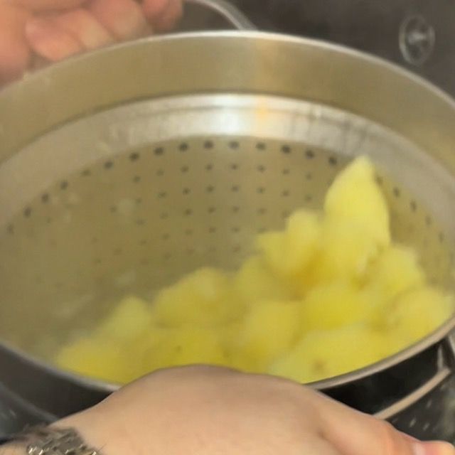 Scolapasta con le patate che viene scosso energicamente per renderle ruvide.