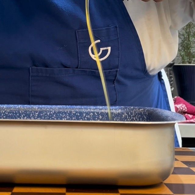 Olio aromatizzato versato in una teglia da forno bassa e larga.