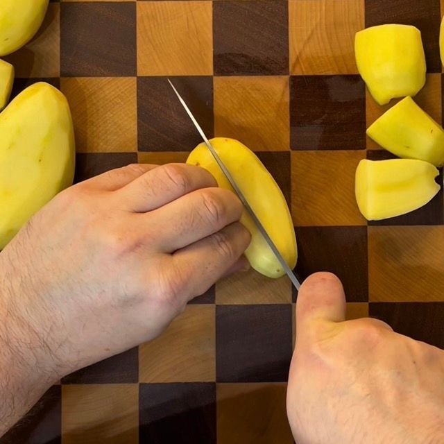 Mano che sbuccia una patata con un pelapatate.