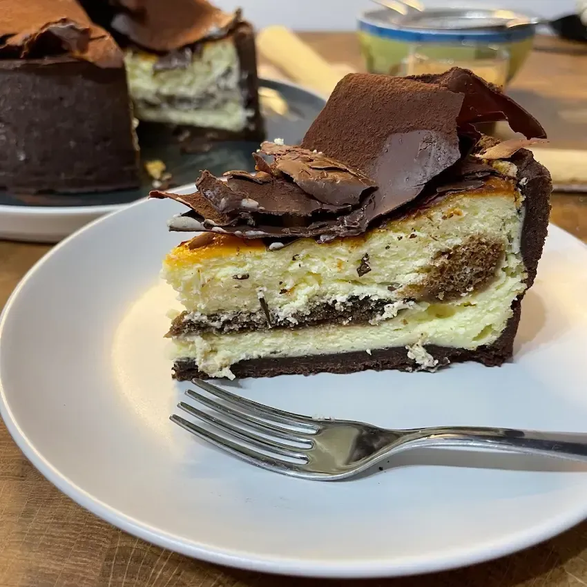 Una fetta di cheesecake su un piatto bianco con una forchetta