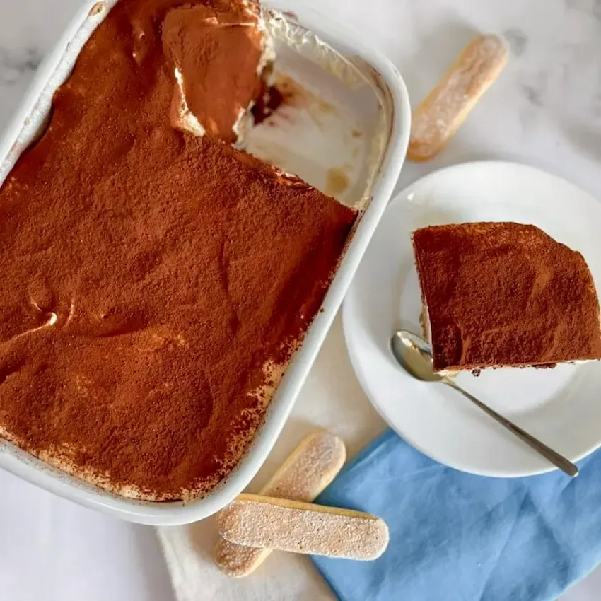 Fetta di tiramisù panna, che mostra la consistenza ariosa e soffice della crema al mascarpone.