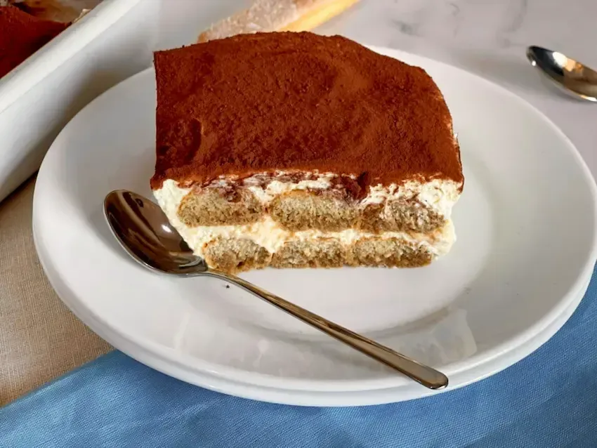 Fetta di tiramisù con panna, che mostra la consistenza ariosa e soffice della crema al mascarpone.