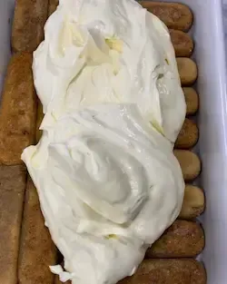 ssemblaggio del tiramisù classico con il primo strato di crema al mascarpone spalmata sui savoiardi.