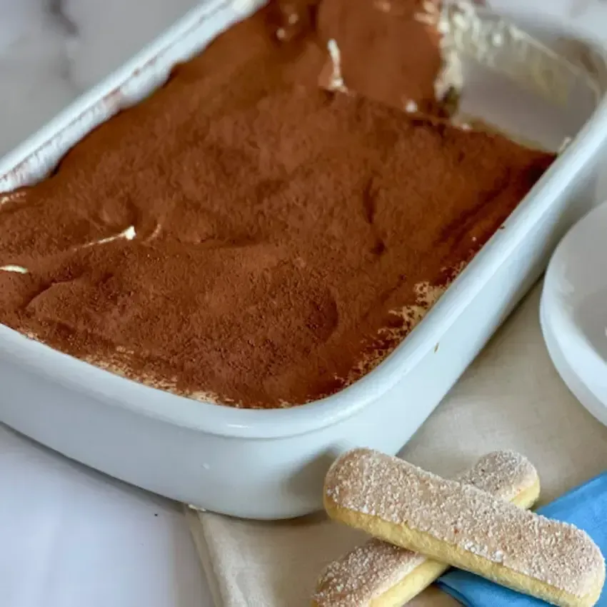 Tiramisù senza glutine fatto in casa in una pirofila di vetro, con una spolverata di cacao amaro in superficie.