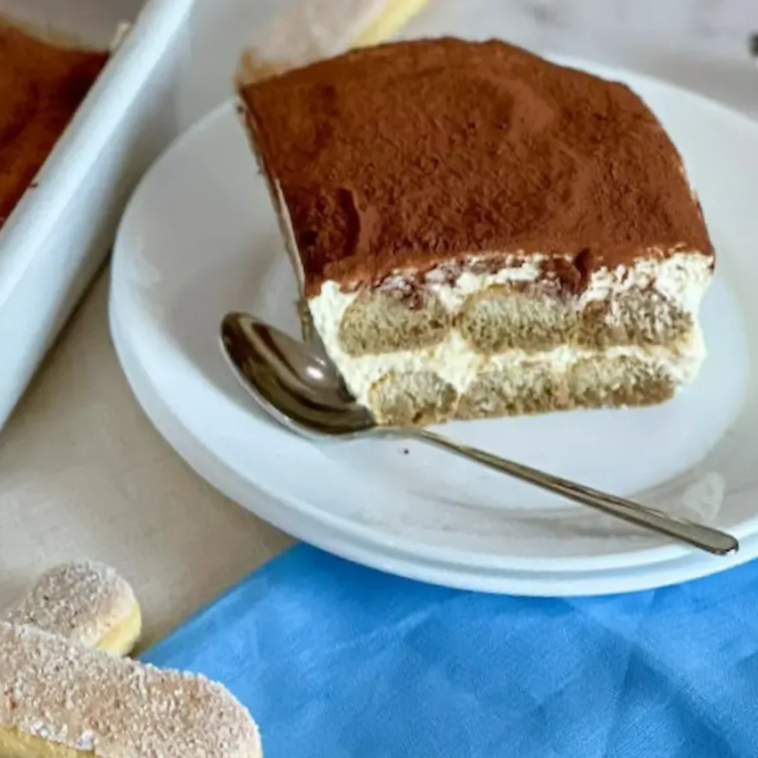 Fetta di tiramisù senza glutine che mostra gli strati perfetti di crema al mascarpone e savoiardi senza glutine inzuppati.