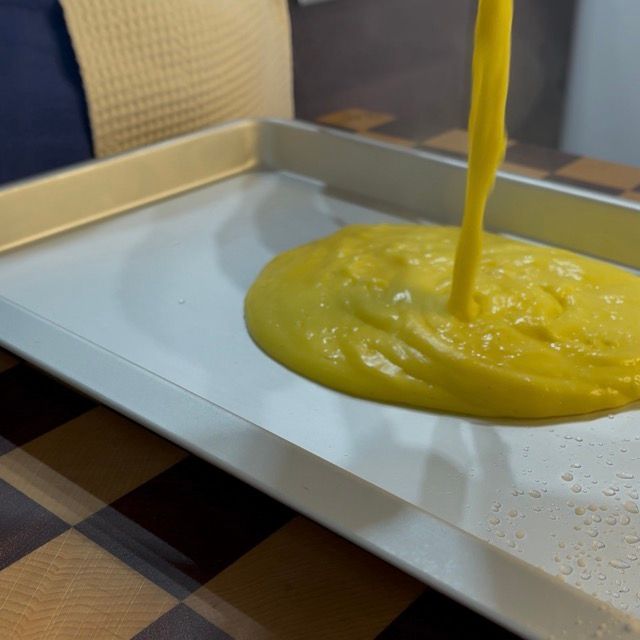 Crema calda versata in una teglia ghiacciata per abbattere la temperatura