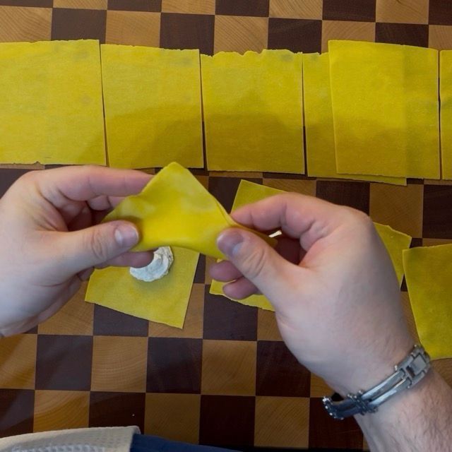 quadrati di pasta fresca all'uovo vengono chiusi come tortelloni