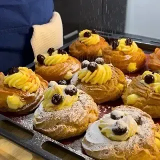 Dettaglio di una zeppola di san giuseppe fritte appena farcita con crema pasticcera e amarena sciroppata.