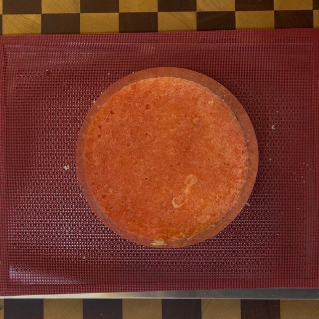 Pennello che inzuppa il pan di spagna con la bagna all'Alchermes.