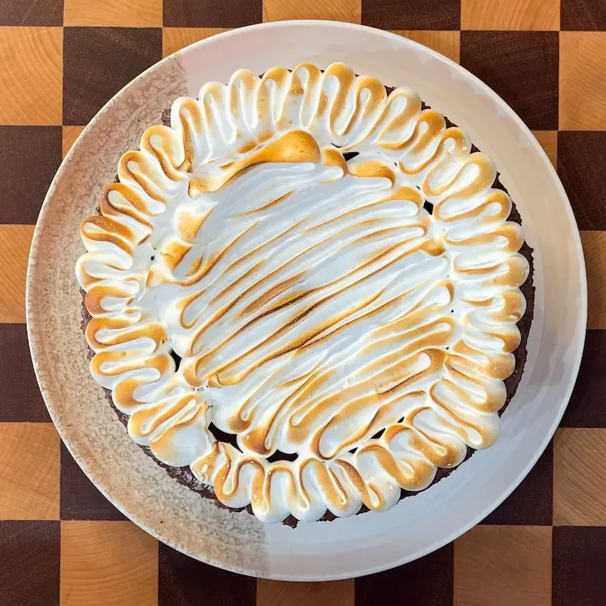 Zuppa Inglese in un vassoio che mostra gli strati colorati di crema e la copertura di meringa fiammeggiata.
