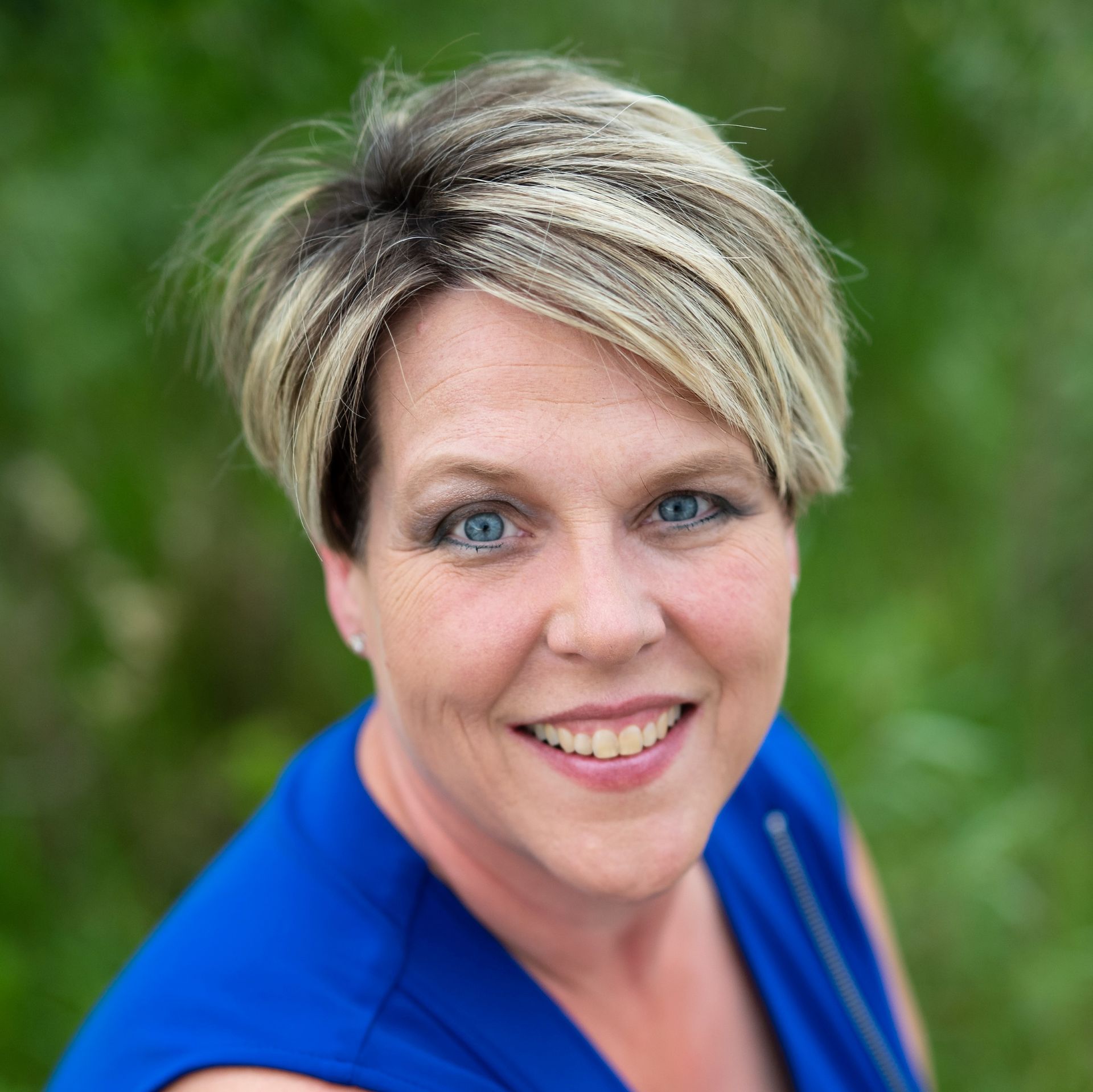 A woman in a blue shirt is smiling for the camera.