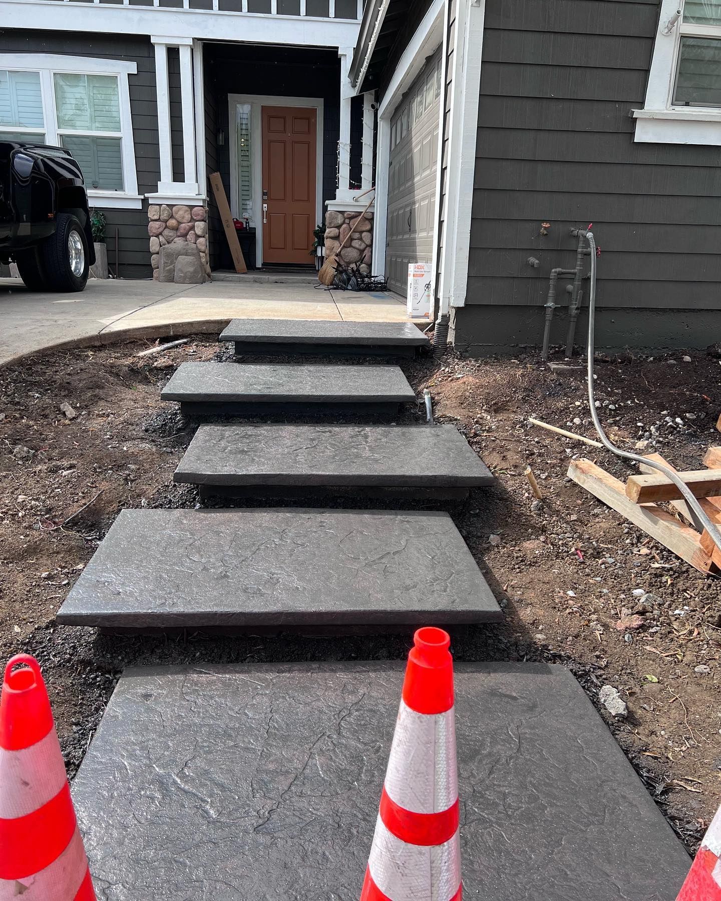 Concrete steps leading to a house entrance, flanked by orange traffic cones in the foreground.