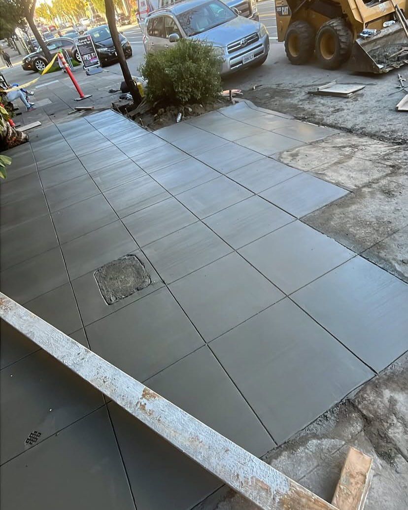 A temporary ground protection mat system laid out over an uneven dirt surface near a street with parked cars.
