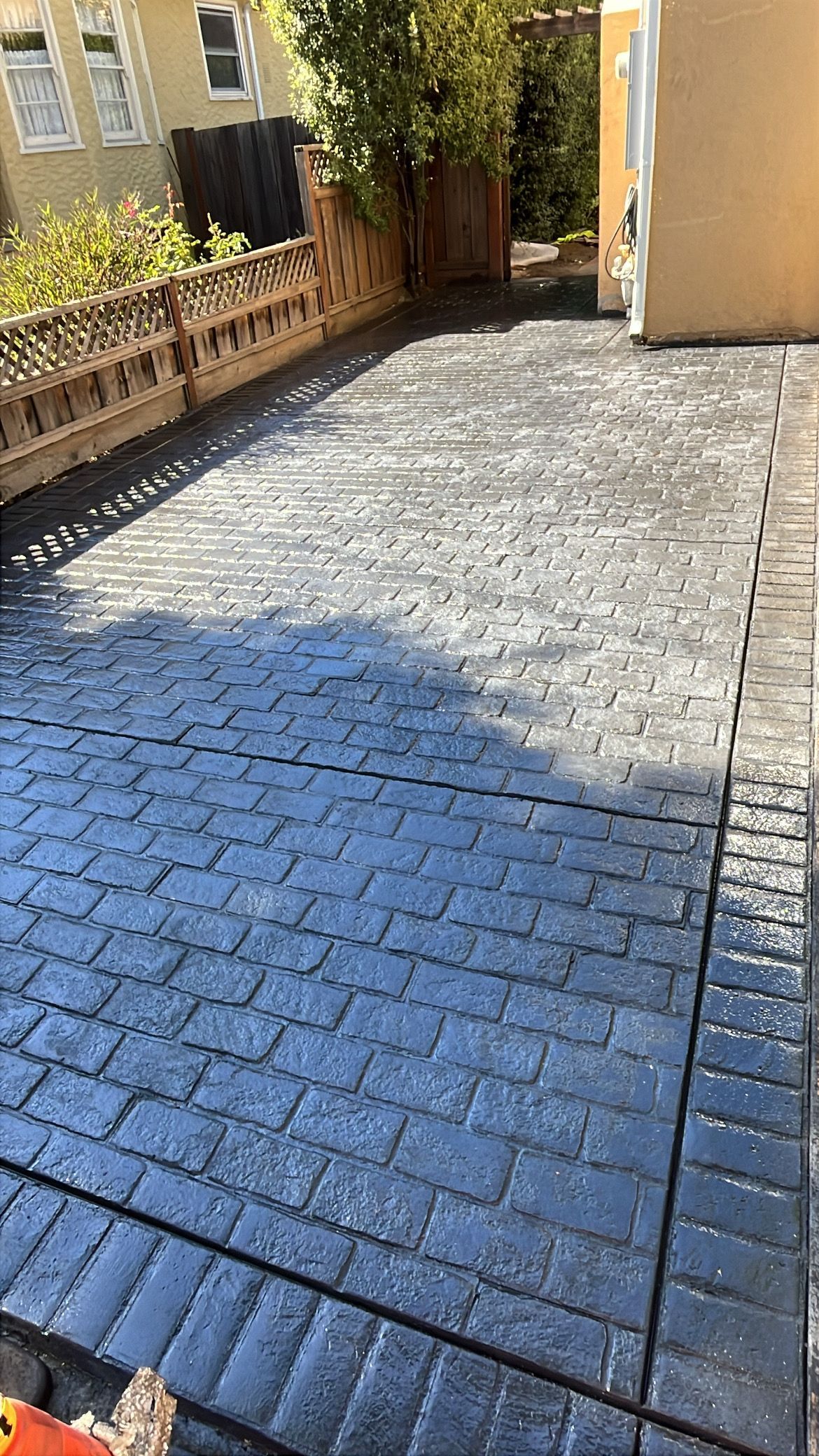 A winding stone path leads through a lush, vibrant green garden with colorful flowering bushes and tall palm trees.