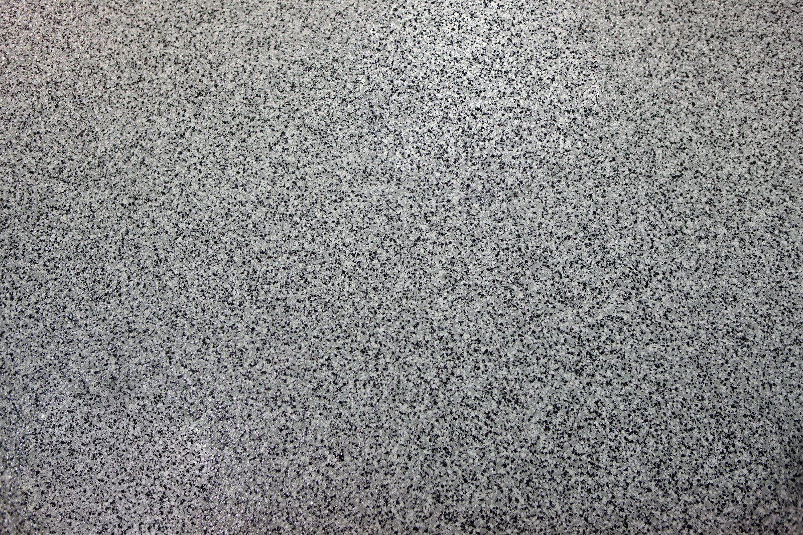 A close-up, high-angle view of a grey and black speckled granite surface with a uniform, textured pattern.