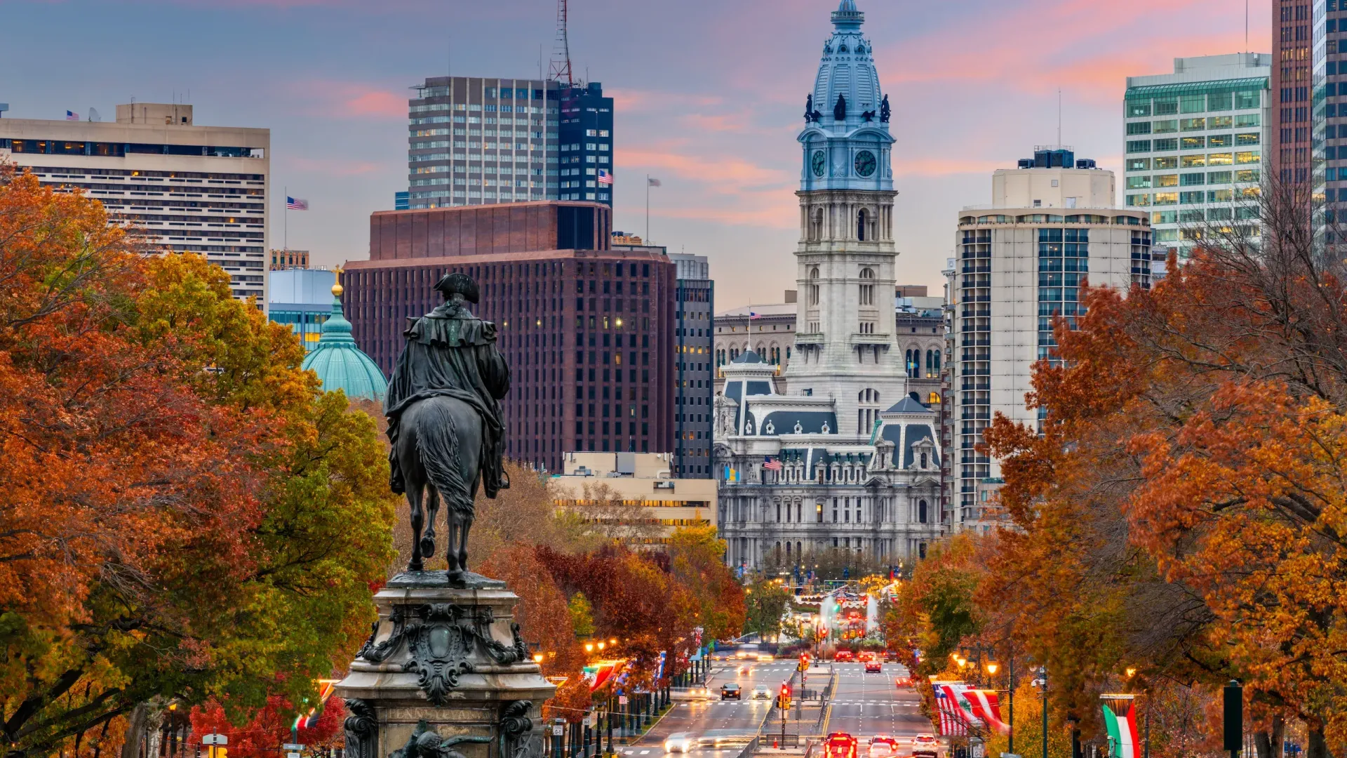 Autumnal view of Philadelphia with a statue, City Hall, and colorful trees.