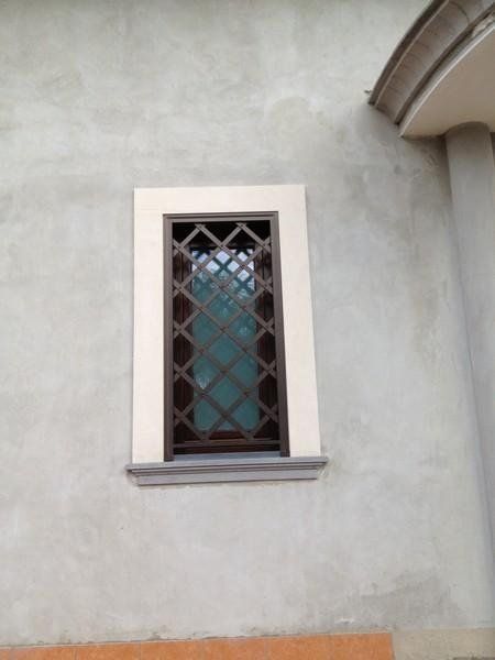 finestra con grata e cornice bianca in pietra