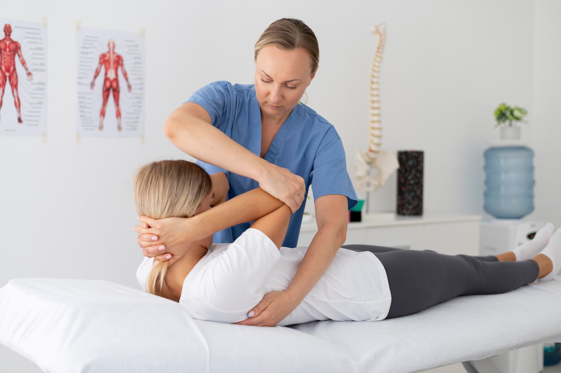 A woman is laying on a bed getting a massage from a nurse.