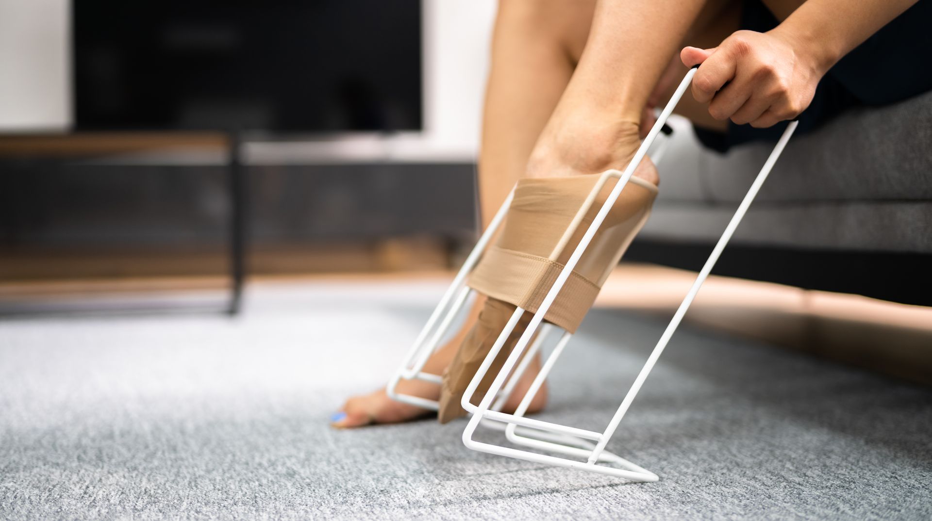 A woman is sitting on a couch putting on stockings.