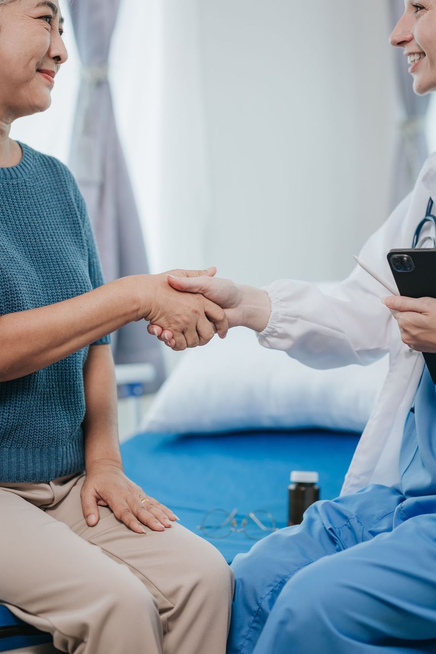 A doctor and a patient are shaking hands while sitting on a bed in Guelph, ON