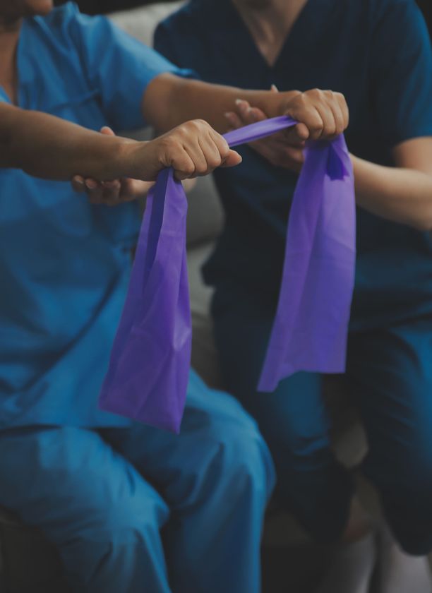 Two people in blue scrubs are holding purple bags in their hands.