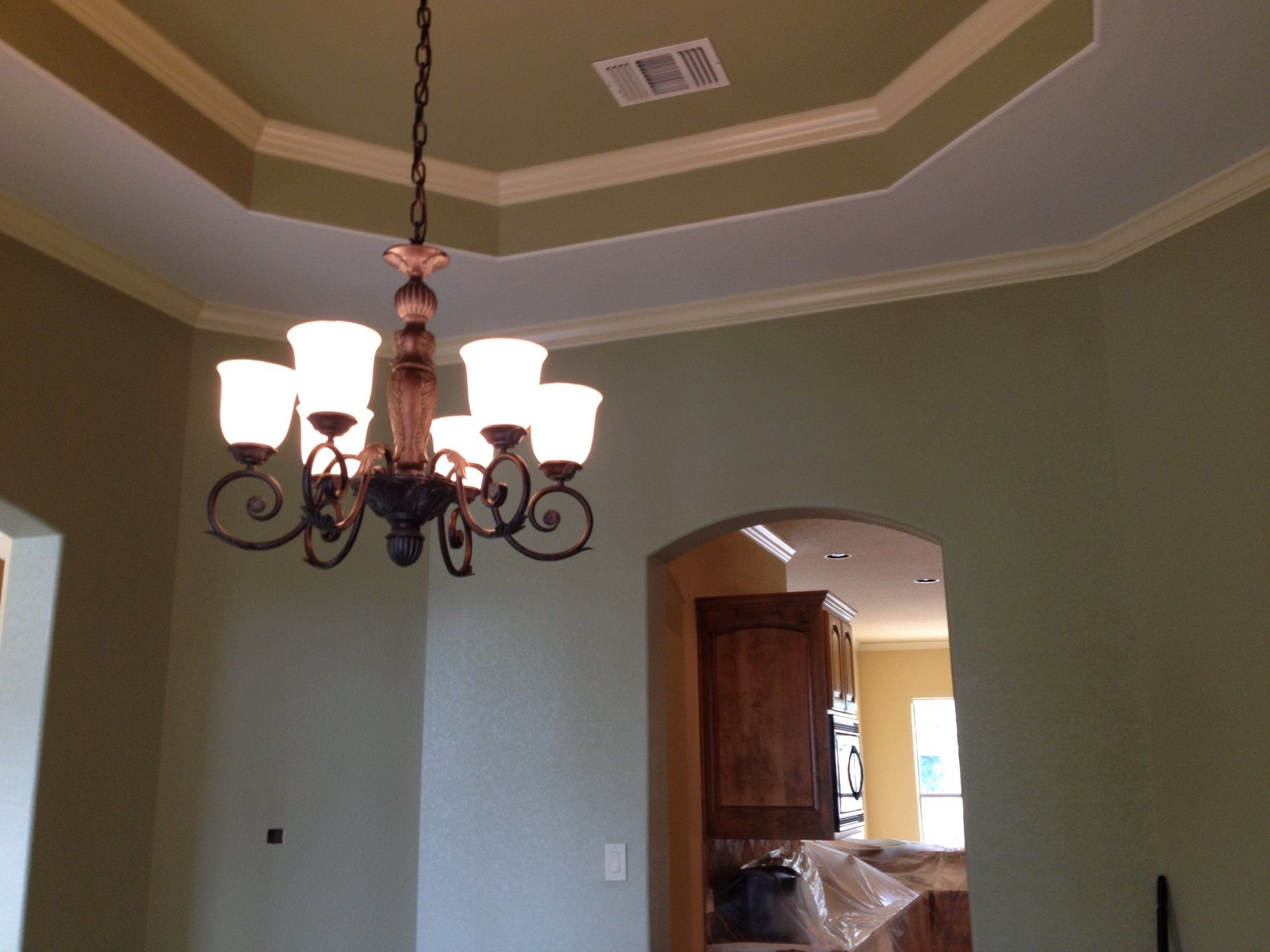 Dining room with chandelier, green walls, and a decorative ceiling.