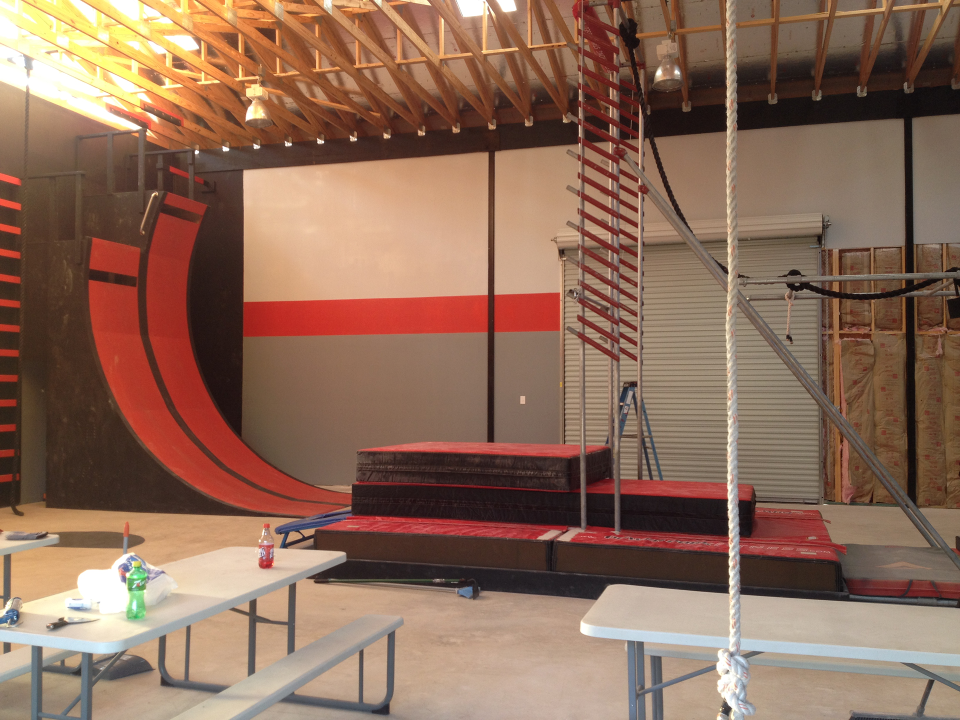 Indoor obstacle course with red, black, and gray elements; a ramp, steps, and ladder.