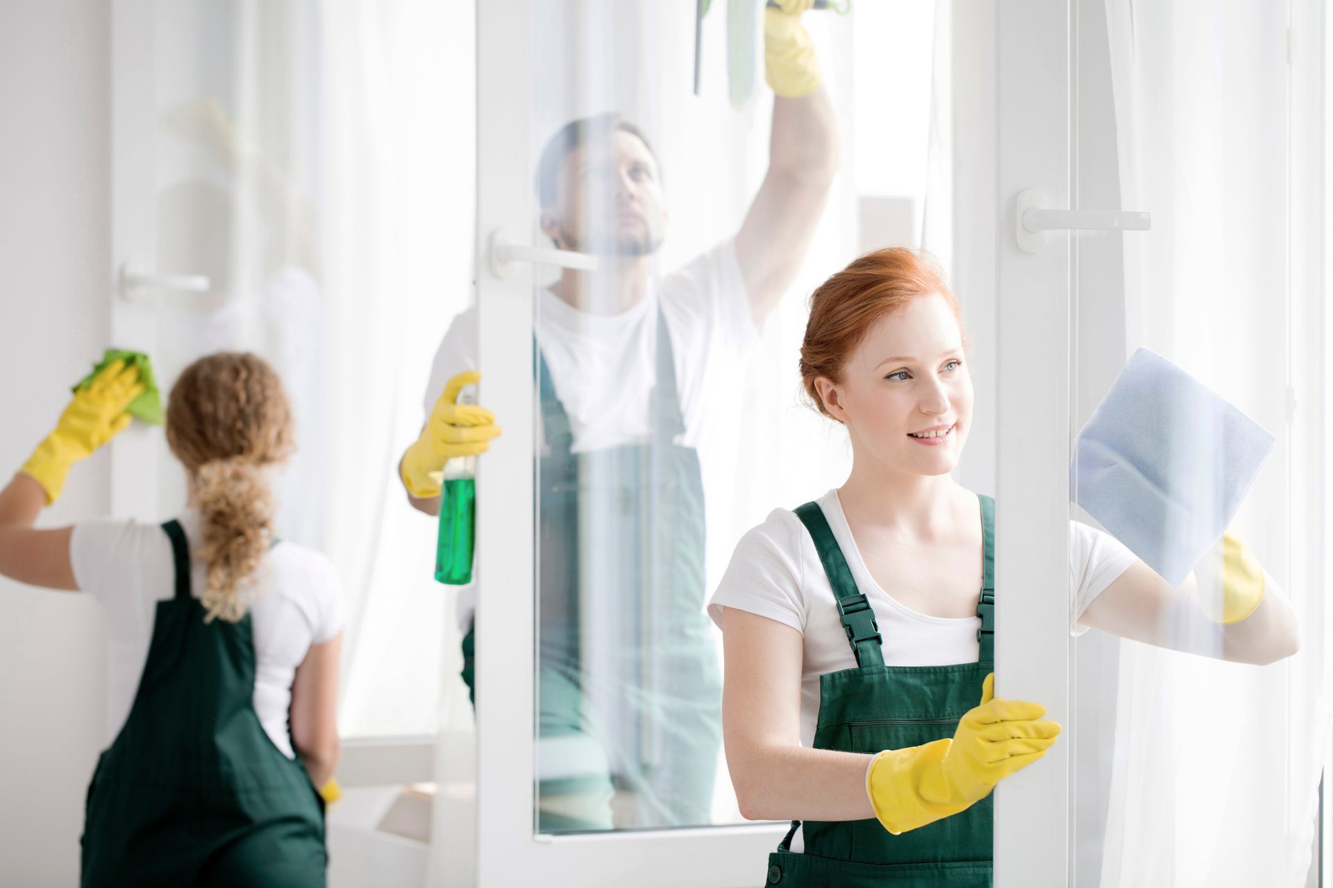 A man and a woman are cleaning a window together.
