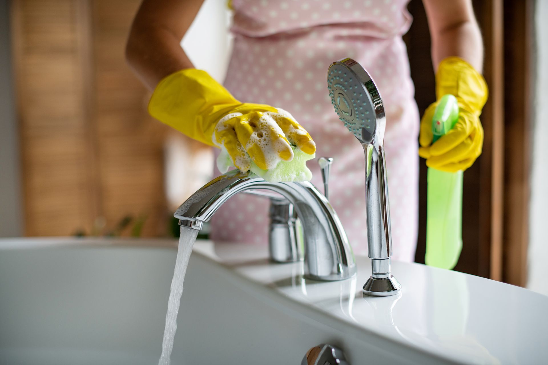 Cleaning a bathroom faucet with a sponge.
