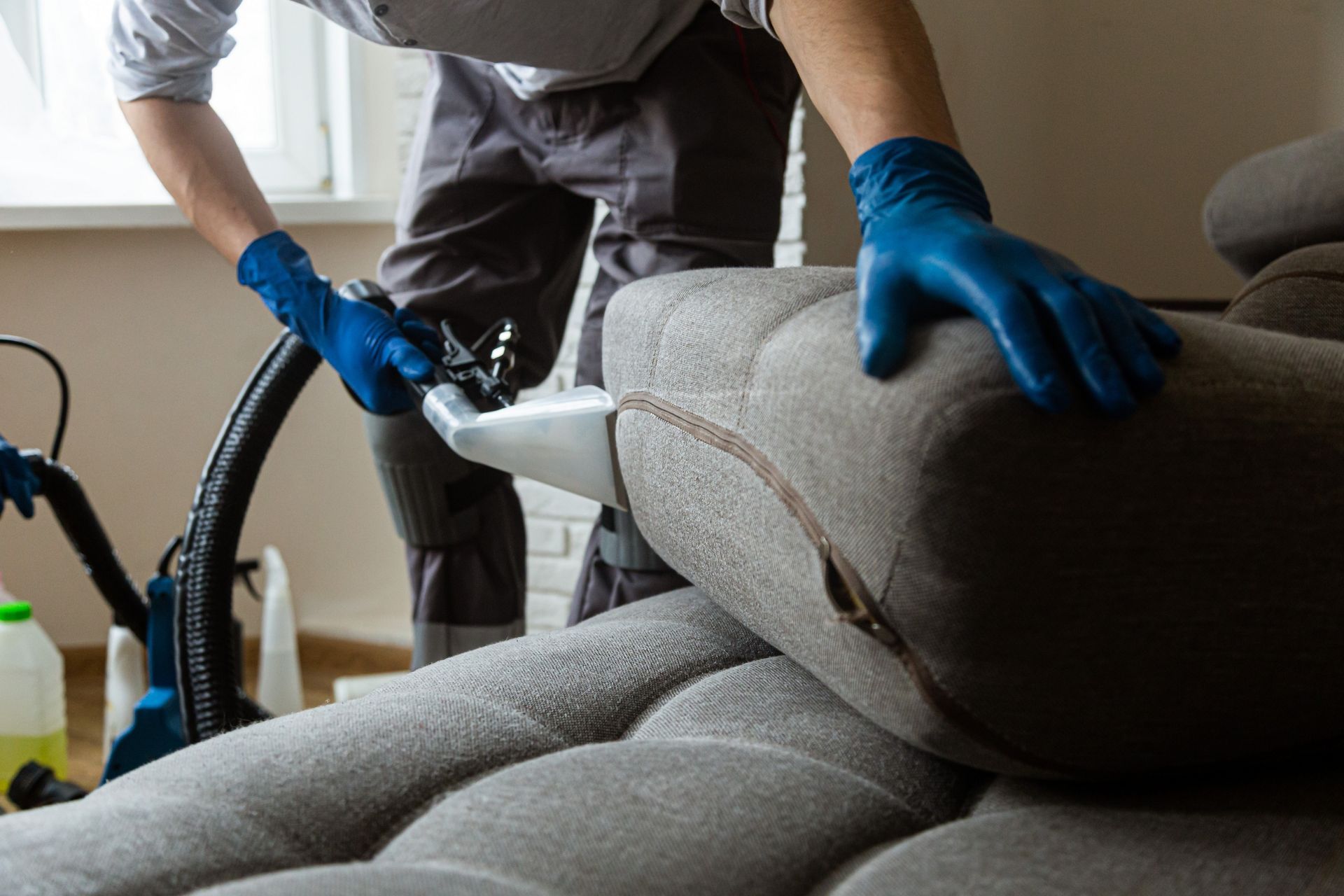 Cleaning a couch with a vacuum cleaner.
