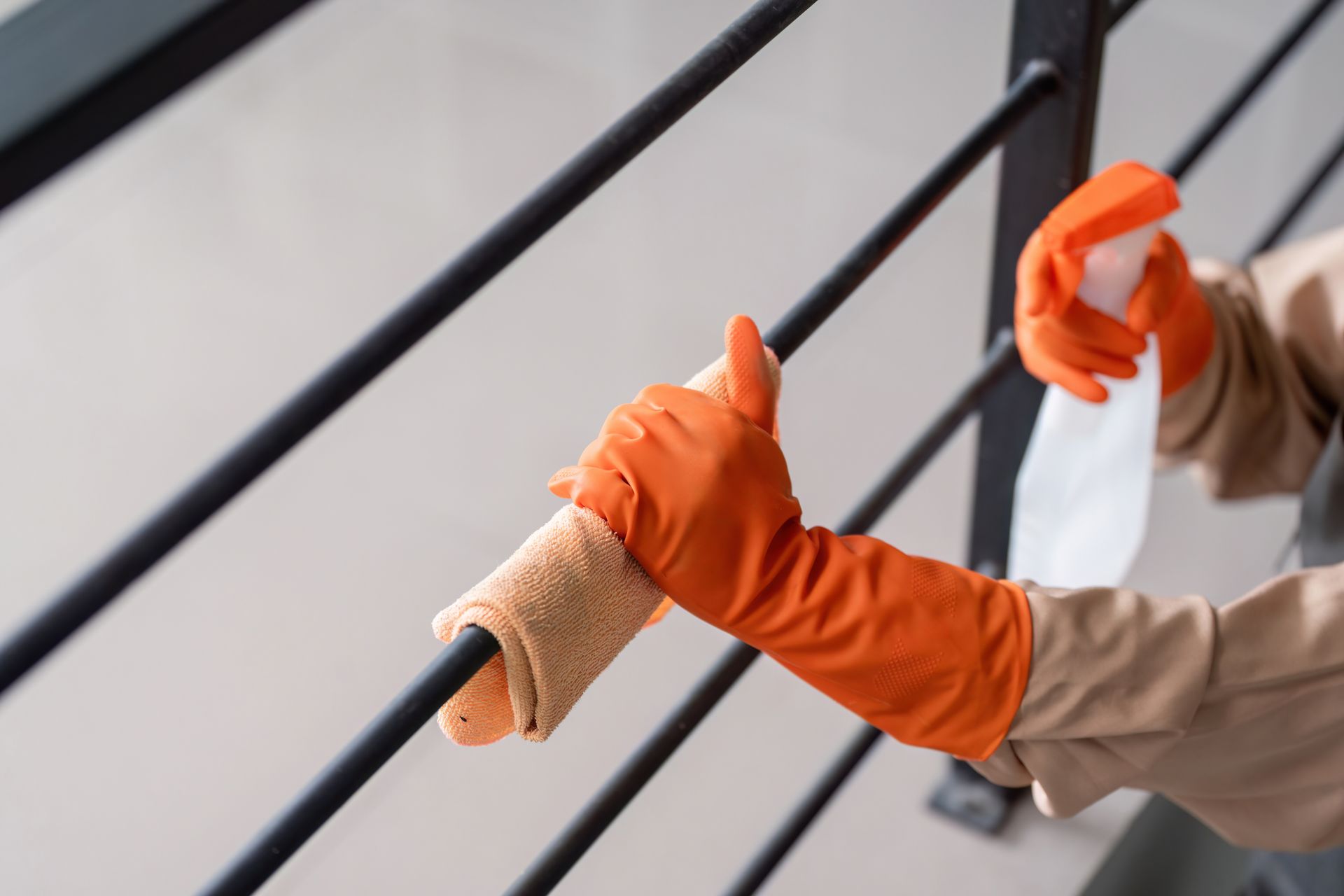 Cleaning a railing with a towel and spray bottle.