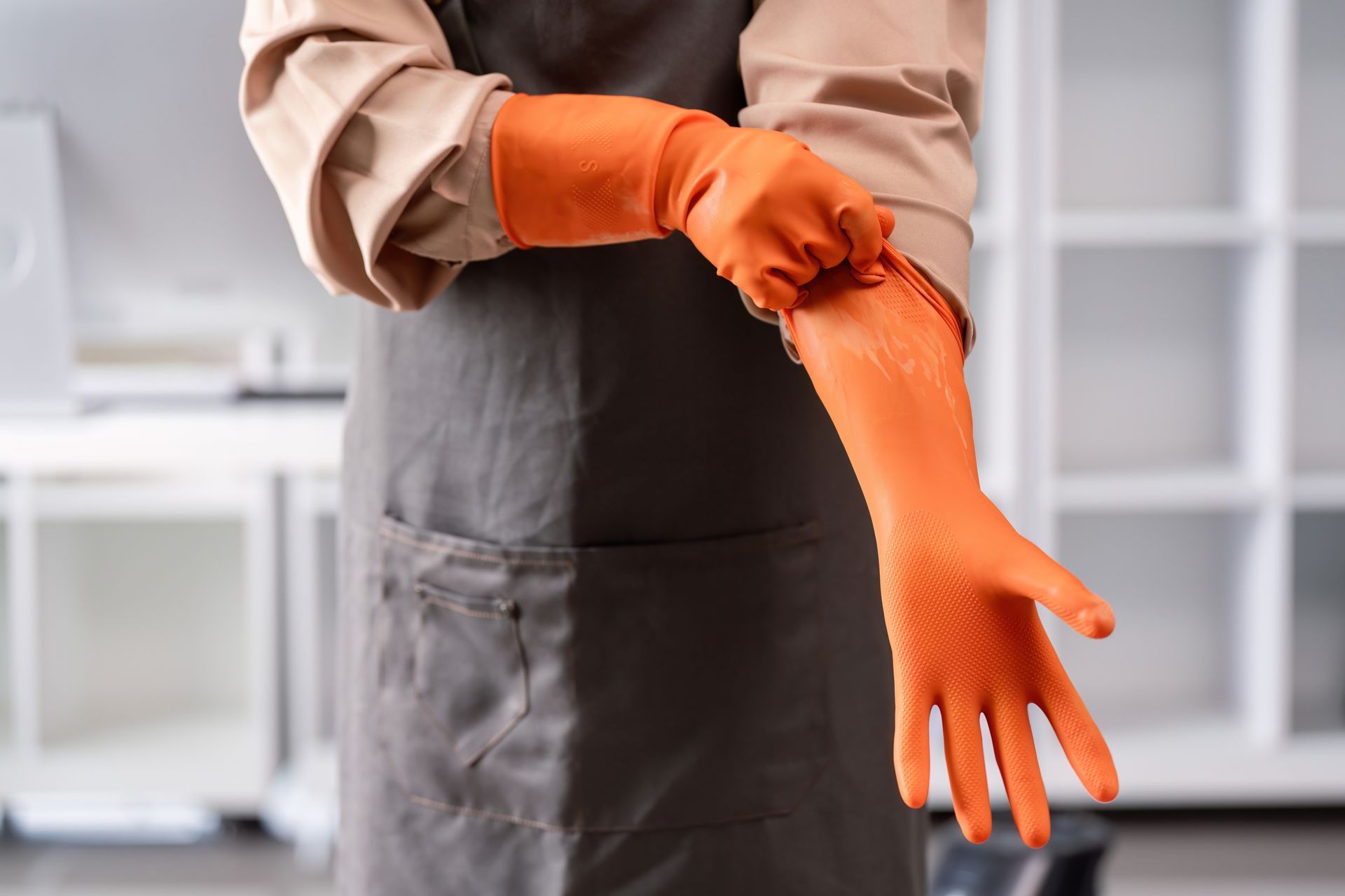 Wearing an apron and orange rubber gloves.