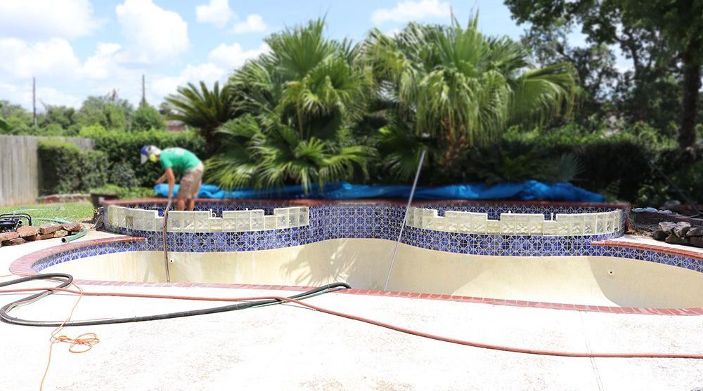 A man is working on the side of a swimming pool.