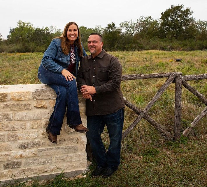 A man and a woman are standing next to each other on a stone wall.