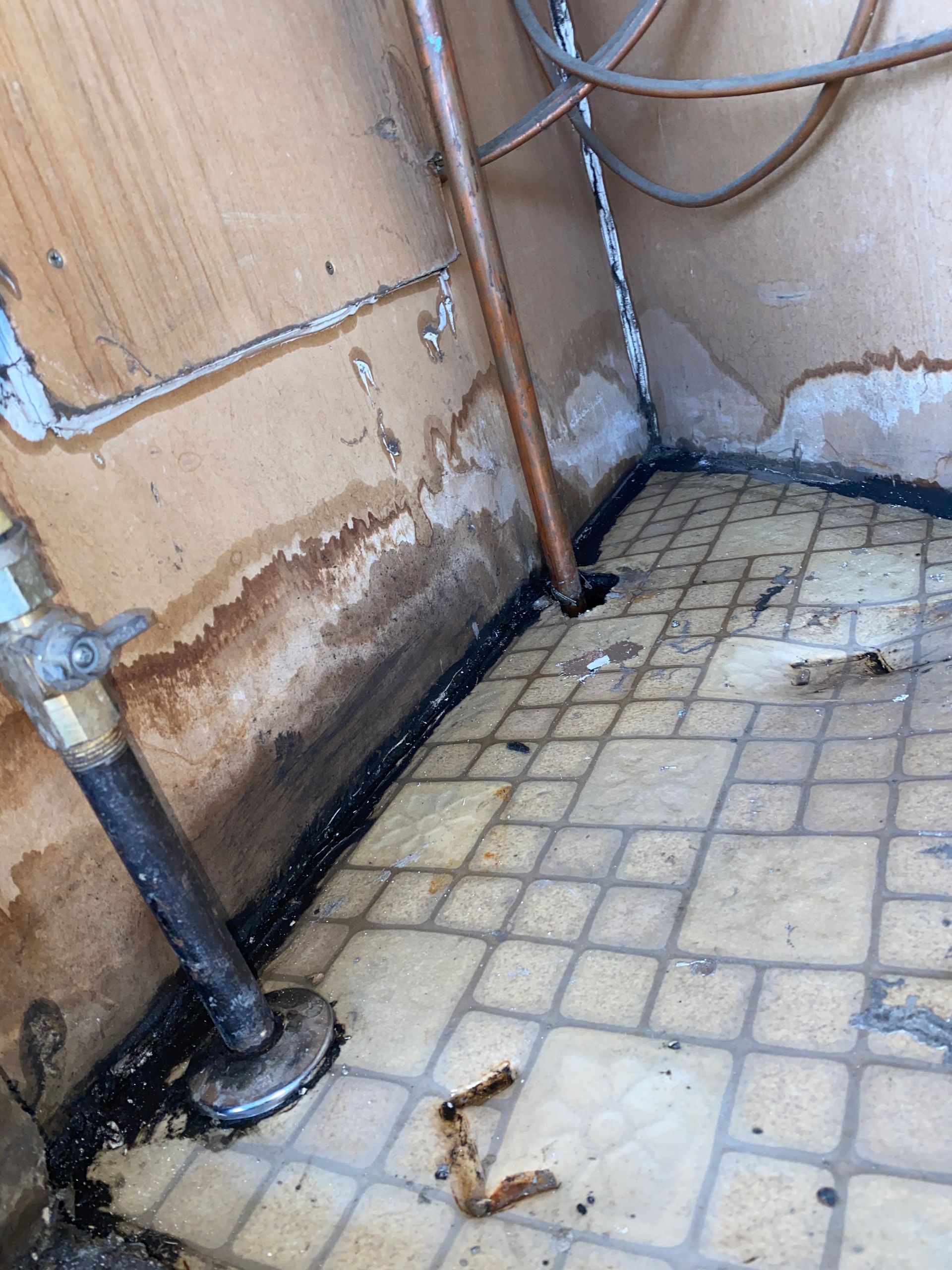 A dirty room with a tiled floor and a pipe.