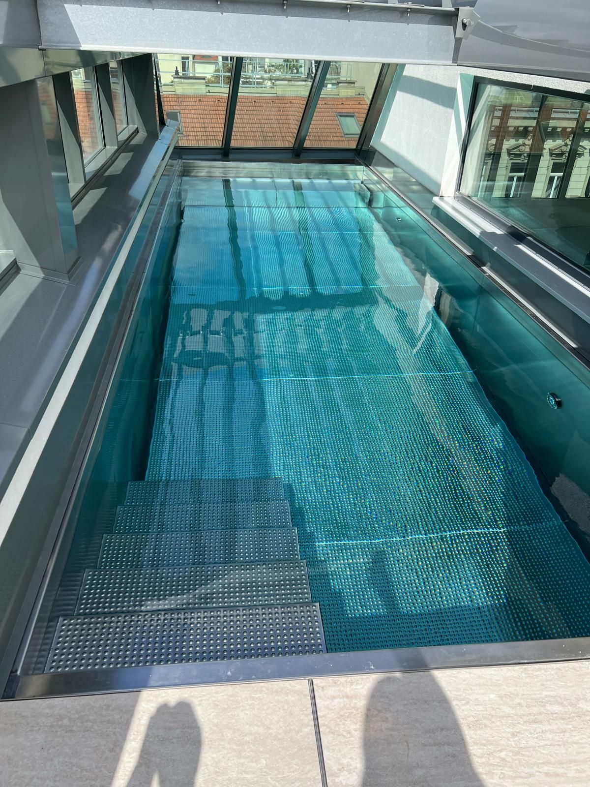 Eine Holztreppe neben einer weißen Küche in einem lichtdurchfluteten Raum mit Holzboden.