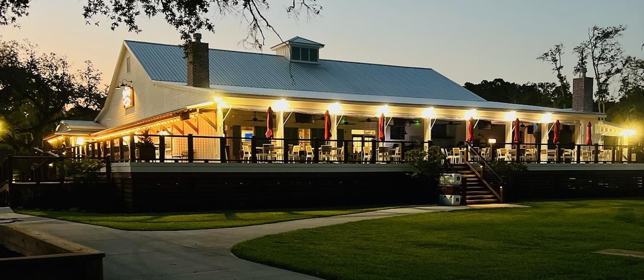 A large white house with a blue roof is lit up at night.
