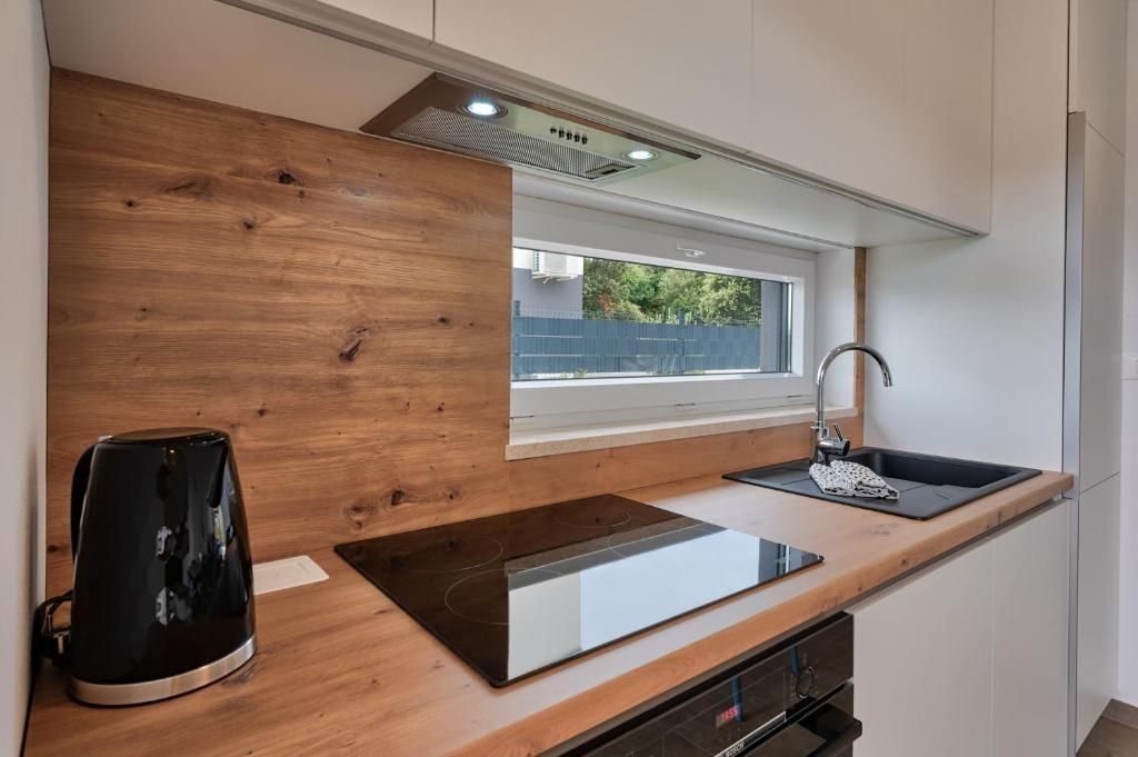 Kuhinja s štedilnikom, pečico, pomivalnim koritom in oknom.