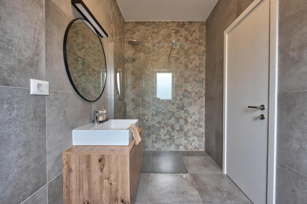 Kopalnica z umivalnikom, ogledalom in tušem.