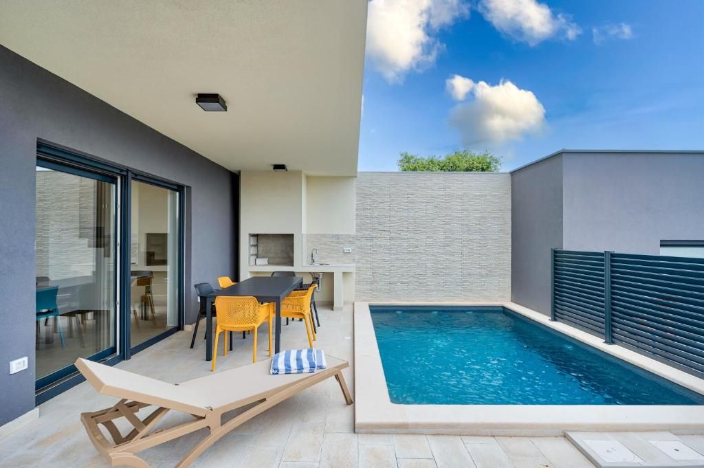 Velik bazen je obdan s teraso z mizo in stoli.